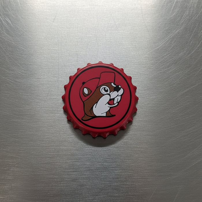 A red Bottle Cap Opener that has the Buc-ee's logo on the front with a bottle cap style.
