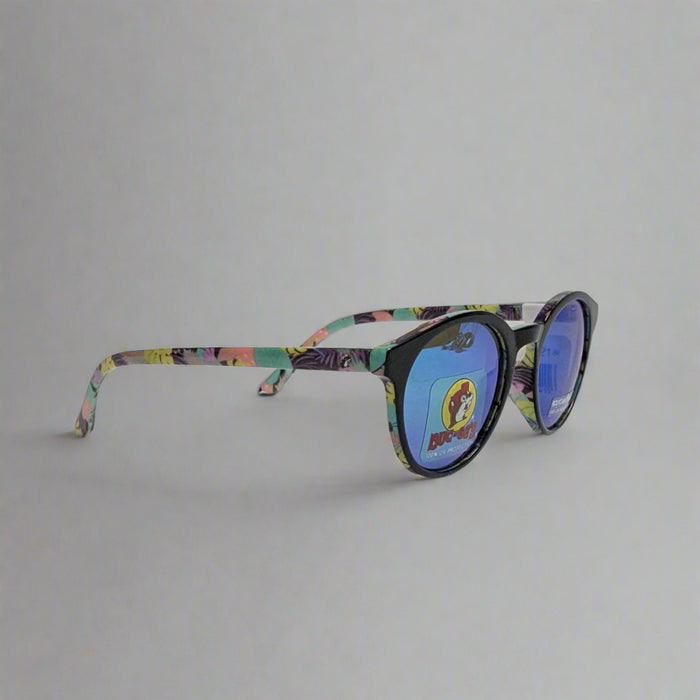 Buc-ee's Tropical Sunglasses. Tropical leaves and plants on sides with purple, pink, yellow, teal.