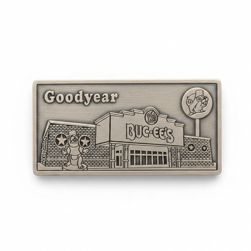 Metallic embossed design of a building with 'Goodyear' branding on a wooden surface