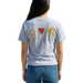 Person wearing a gray t-shirt with peace, love, and friendship patches in front of a gas station.