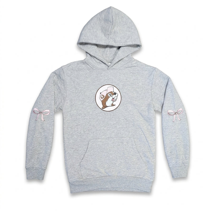 Front view of an adult heather gray Buc-ee's pullover hoodie featuring a small pink beaver logo centered on the chest, a front kangaroo pocket, and pink ribbon bows printed on each sleeve.