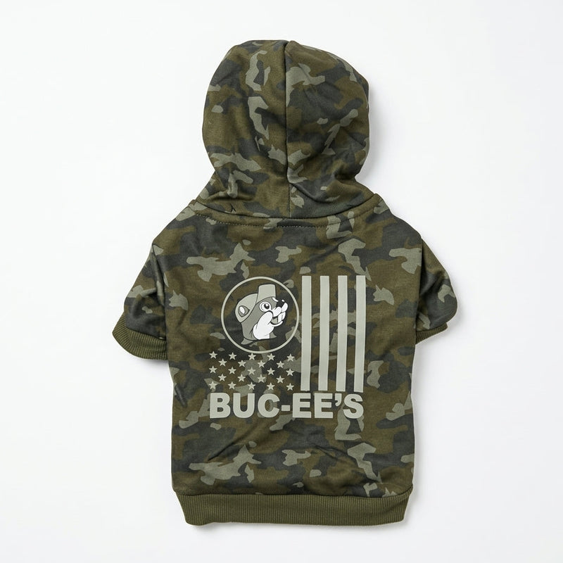 Back view of a green camo pet hoodie laid flat, showing a white US flag-inspired print featuring Buc-ee the Beaver and "BUC-EE'S" text across the back.