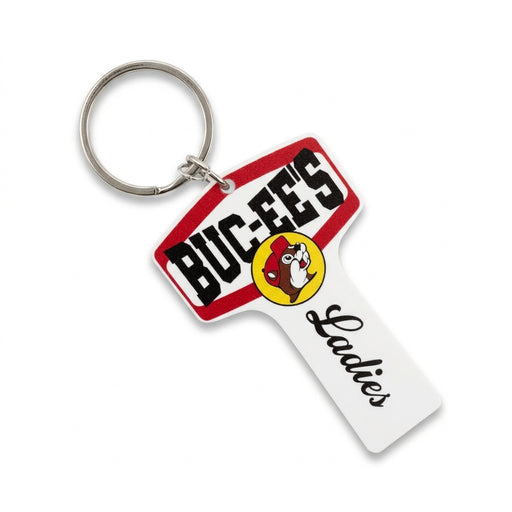 An oversized white plastic key ring styled like a restroom key, featuring the Buc-ee's beaver logo, red borders, and "Ladies" written in black script.