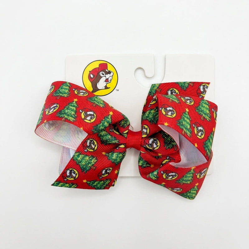 Medium red grosgrain hair bow featuring an all-over pattern of Santa Buc-ee logos and Christmas trees with a clip backing.
