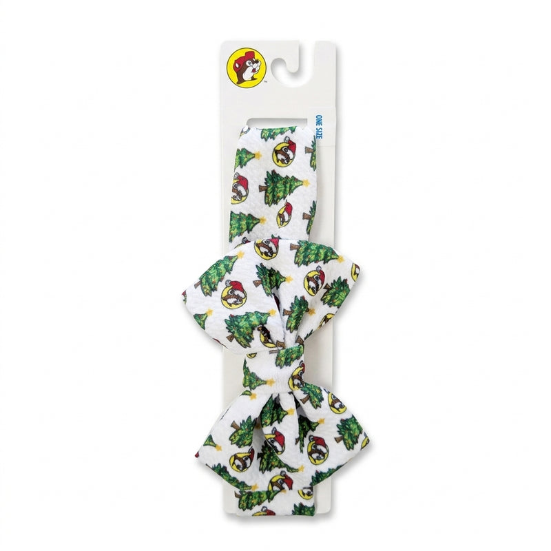 White textured fabric headband with an all-over pattern of Santa Buc-ee logos and Christmas trees styled with a top bow, displayed on a packaging card.