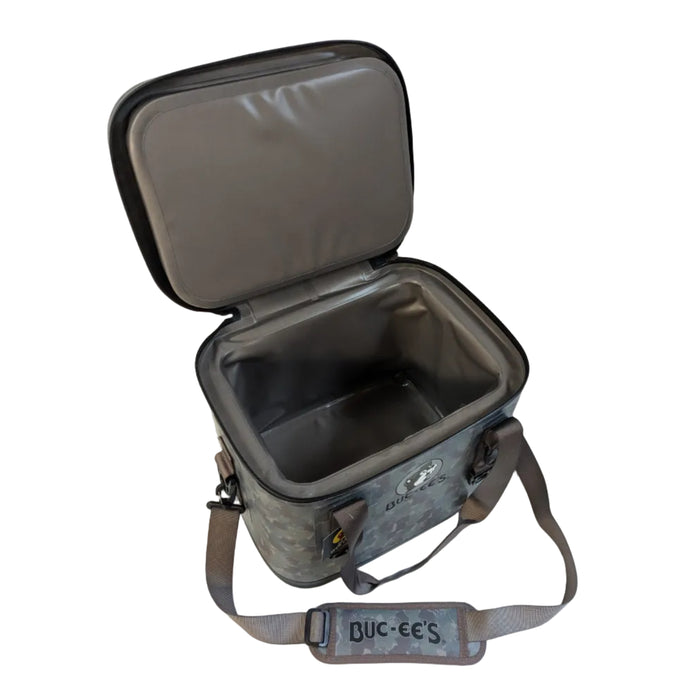 A high-angle product photograph of the camo Buc-ee's 30 Can Tech Cooler with its top lid fully unzipped and propped open. The image highlights the spacious, seamless grey insulated interior and thick, leakproof zipper track. A wide, matching camo shoulder strap with a padded section reading "BUC-EE'S" in bold black text is laid out in front of the cooler on a white background.