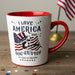 White mug with red interior and handle on top of cardboard boxes