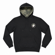 Front view of a black pullover hoodie featuring a small circular Buc-ee's camo hat logo on the left chest, a front pouch pocket, and a green camouflage hood lining.
