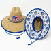 A product photograph of two Buc-ee's straw lifeguard hats against a plain white background. One hat is shown from the front, featuring a woven straw texture and a rectangular patch with an American flag background and the Buc-ee’s beaver mascot. The second hat is tilted to show the underside of the wide brim, which is lined with a vibrant blue and white fabric featuring a repeating pattern of the Buc-ee’s mascot and red and blue stars. Both hats include a blue adjustable chin cord with a wooden bead.