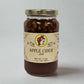 A 17 oz. jar of Apple Cider Jam with a golden lid, featuring a label adorned with a playful mascot and "Apple Cider Jam" text, showcasing its rich, spiced apple filling.