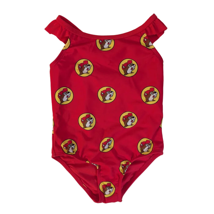 A flat lay product photograph of a Buc-ee's Baby Girl Red Logo one-piece swimsuit on a clean white background. The swimsuit features ruffle details on the shoulder straps and is covered in a dense, repeating pattern of the yellow and red Buc-ee’s beaver logo. 