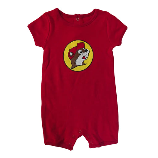 A flat-lay view of a bright red short-sleeve baby romper on a white background. The center of the chest features the yellow circular Buc-ee's beaver logo. The romper has snap closures at the bottom and snaps at the collar.