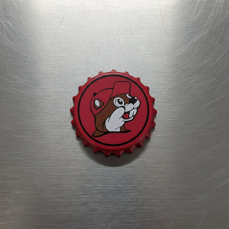 A red Bottle Cap Opener that has the Buc-ee's logo on the front with a bottle cap style. 