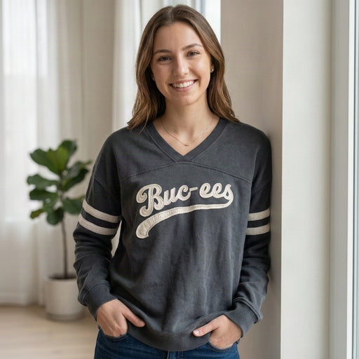 Woman leaning against a wall wearing a black & white Buc-ee's v-neck tunic