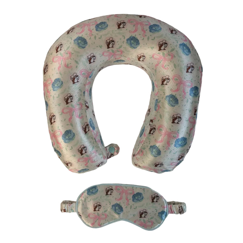 A travel sleep set consisting of a U-shaped neck pillow and a matching eye mask. Both items are made of a very light green fabric featuring a repeating "Blossoms and Bows" pattern of pink ribbons, blue flowers, and the Buc-ee's beaver mascot. Displayed on a clean white background.