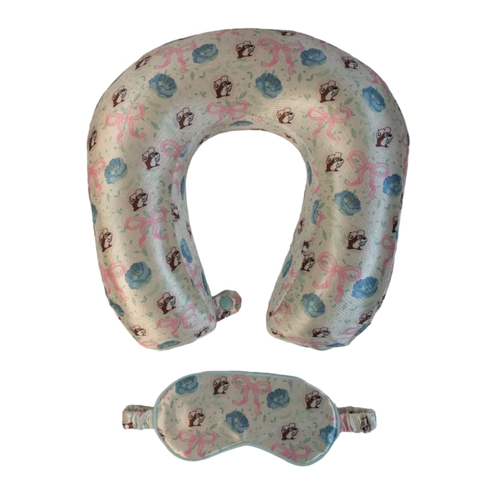 A travel sleep set consisting of a U-shaped neck pillow and a matching eye mask. Both items are made of a very light green fabric featuring a repeating "Blossoms and Bows" pattern of pink ribbons, blue flowers, and the Buc-ee's beaver mascot. Displayed on a clean white background.
