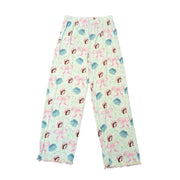 A top-down view of the Youth Blossoms & Bows Pajama Pants. These pants feature a very light green fabric with an all-over print of pink bows, blue flowers, and the Buc-ee's beaver mascot. They have a simple, flat elastic waistband without a drawstring and a ruffled, pink lettuce-edge hem at the ankles. Displayed on a clean white background.