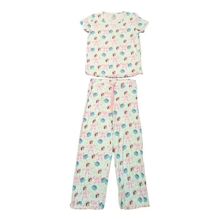 A top-down view of the Adult Blossoms & Bows Pajama Set pieces. A light green short-sleeve shirt is positioned above the matching pajama pants. Both pieces feature the signature pattern of pink bows, blue flowers, and the Buc-ee's beaver mascot. The pants include a functional pink drawstring at the waist, and both the shirt and pant cuffs are finished with a ruffled lettuce-edge hem. Displayed on a clean white background.