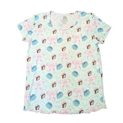 A top-down view of the Adult Blossoms & Bows Short Sleeve Pajama Shirt. The shirt is a very light green with a repeating pattern of pink bows, blue flowers, and the Buc-ee's beaver mascot wearing a matching hat. It features a classic crew neckline and a ruffled, pink lettuce-edge hem at the bottom. Displayed on a clean white background.