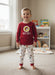 A young boy pictured wearing Buc-ee’s boy’s snug fit pajama set with red long-sleeve Buc-ee’s logo top and white sports-print pants featuring footballs, basketballs, soccer balls, and “82” accents.