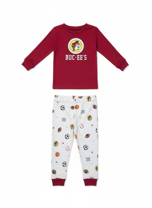 Buc-ee’s boy’s snug fit pajama set with red long-sleeve Buc-ee’s logo top and white sports-print pants featuring footballs, basketballs, soccer balls, and “82” accents, displayed on a clean white background.