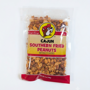 A 7 oz clear plastic bag of Buc-ee's Cajun Southern Fried Peanuts, featuring the round yellow beaver mascot logo on a yellow and red label, showing the seasoned red-tinted peanuts inside.