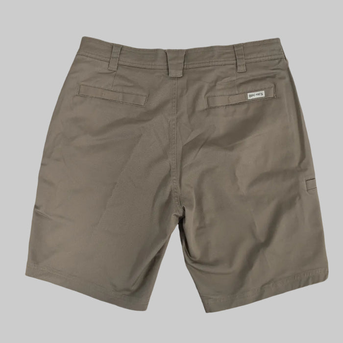 A back view of the Buc-ee's Caribou Fishing Twill Shorts in a deep earth-brown taupe, shown laid flat against a neutral grey background. The image highlights the clean, durable construction of the cotton-twill fabric, featuring two horizontal welted back pockets and reinforced belt loops. A small, white rectangular "Buc-ee's" logo patch is sewn above the right rear pocket. On the far right edge, the side-entry utility tool slot is partially visible.