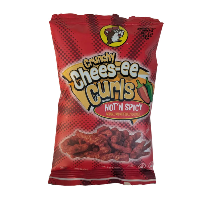 A 2 oz bag of Buc-ee’s "Crunchy Chees-ee Curls" in Hot 'N Spicy flavor. The bag is solid red with a black halftone pattern. The design includes a graphic of two chili peppers (one red, one green). The crunchy corn curls at the bottom have a deep red, spicy coating. Displayed on a clean white background.