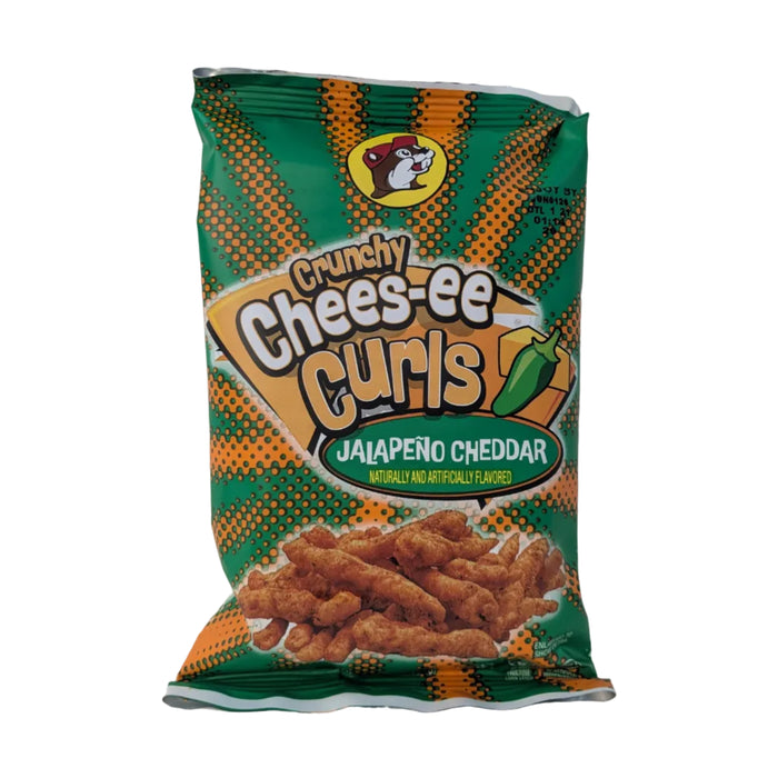 A 2 oz bag of Buc-ee’s "Crunchy Chees-ee Curls" in Jalapeño Cheddar flavor. The bag is green with an orange halftone pattern and features a graphic of a green jalapeño pepper next to a wedge of cheese. Darker, textured crunchy corn curls are shown at the bottom. Displayed on a clean white background.