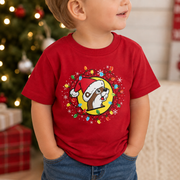 Toddler wearing a red Christmas T-shirt featuring a Santa-hat Buc-ee’s beaver surrounded by colorful holiday lights and snowflakes, shown in a close-up festive setting.