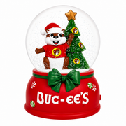 Buc-ee’s Christmas musical snow globe with a Santa-hat beaver beside a decorated Christmas tree inside a clear globe, on a red base with a green bow and Buc-ee’s logo.