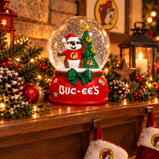Buc-ee's Christmas snow globe glowing on a mantel among garland and lights