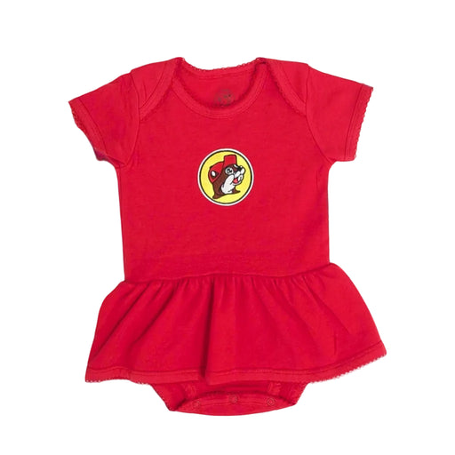 A flat-lay product photograph centered on a white background showing a vibrant red Buc-ee's infant onesie dress. The short-sleeve knit bodysuit features a yellow circular patch with the classic cartoon Buc-ee the Beaver logo on the chest. It includes a built-in ruffled skirt, a snap-button bottom closure, and delicate scalloped embroidery details running along all edges, including the neckline, sleeve cuffs, and skirt hem.