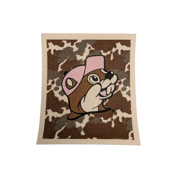 A square Swedish dishcloth featuring a brown and white cowhide pattern background. In the center is the Buc-ee's beaver mascot wearing a light pink baseball cap.