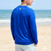 Man wearing a blue long-sleeve shirt with a logo on the beach