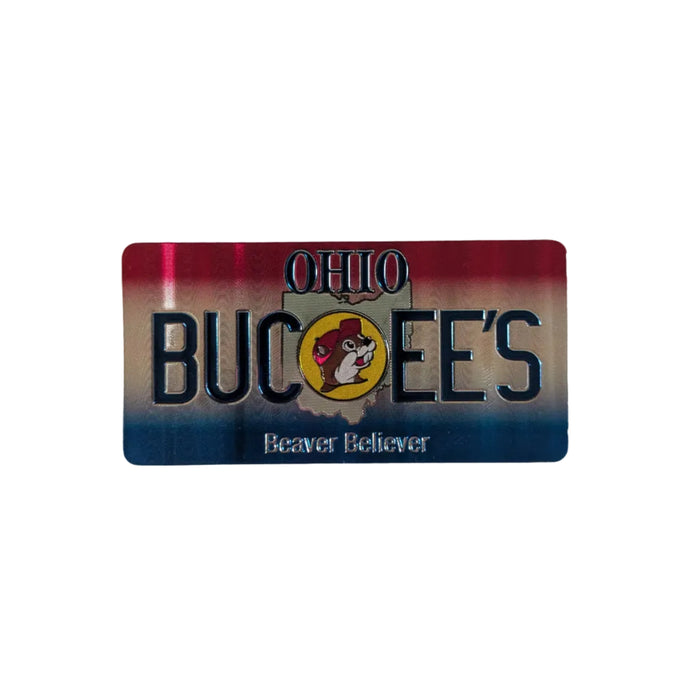 One side of the Buc-ee's Double-Sided  Ohio Magnet, a magnet with a red, silver, and blue gradient background At the top center, the word "OHIO" appears above a large, raised silver "BUC-EE’S" logo. The central circular Buc-ee’s beaver mascot replaces the 'C' and is set against an outline of the state of Ohio. Below the logo, the text "Beaver Believer" is written in silver script. The magnet features rounded corners and sits on a solid white background. 