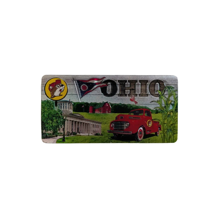 A close-up, top-down shot of one side of the Buc-ee's Double-Sided Ohio Magnet, a rectangular Buc-ee's Ohio magnet resting on a white background. The magnet features a scenic illustration including a vintage red pickup truck, the Ohio state flag, the state capitol building, and a red barn, with the word "OHIO" and the iconic Buc-ee's beaver logo at the top.