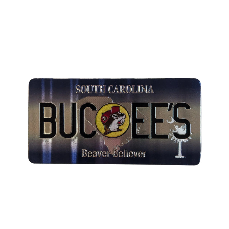 One side of a double-sided rectangular magnet displayed on a plain white surface. This side features a dark navy blue and grey vertical striped background with bold black text reading "BUC-EE'S", the tagline "Beaver Believer", and a small circular Buc-ee's beaver mascot logo.