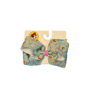 Pastel Teal Buc-ee’s Medium Easter hair bow. The vibrant teal ribbon is decorated with spring daisies and multicolored Easter eggs and the Buc-ee’s beaver logo wearing a purple hat.. The center of the bow is tied with a contrasting pink fabric knot, and it is mounted on a white "Buc-ee’s" branded display card. Displayed on a clean white background.