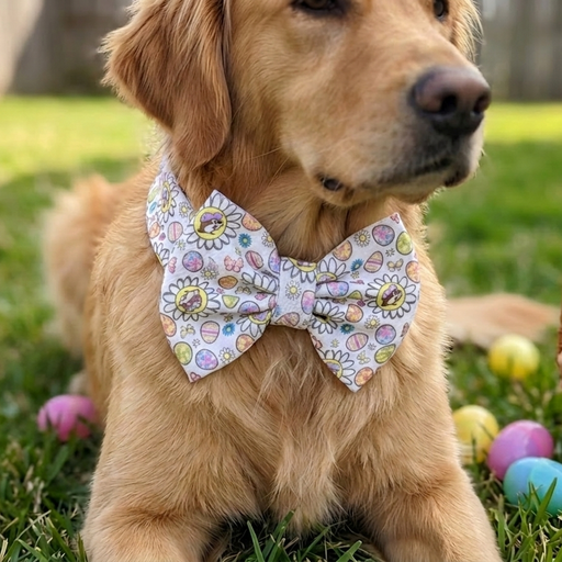 A close-up lifestyle photo of a Golden Retriever dog lying in green grass, wearing the Buc-ee’s white floral headband styled as a charming bow tie around its neck. The fabric features a Spring pattern of daisies, colorful Easter eggs, and the Buc-ee's beaver logo, now updated with a pastel purple hat. Bright plastic Easter eggs are scattered in the grass around the dog.