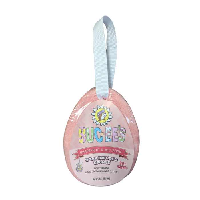 An egg-shaped soap-infused sponge in a pink, spring-themed wrapper with a white ribbon loop for hanging. The label features a cartoon Buc-ee beaver in a daisy, with the text 'BUC-EE'S GRAPEFRUIT & NECTARINE SOAP INFUSED SPONGE' and '30+ WASHES'. Displayed on a clean white background.
