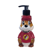 A clear and red figural liquid hand soap dispenser shaped like the Buc-ee's beaver mascot wearing a red hat and shirt, filled with golden amber Honey Almond soap and topped with a black pump.