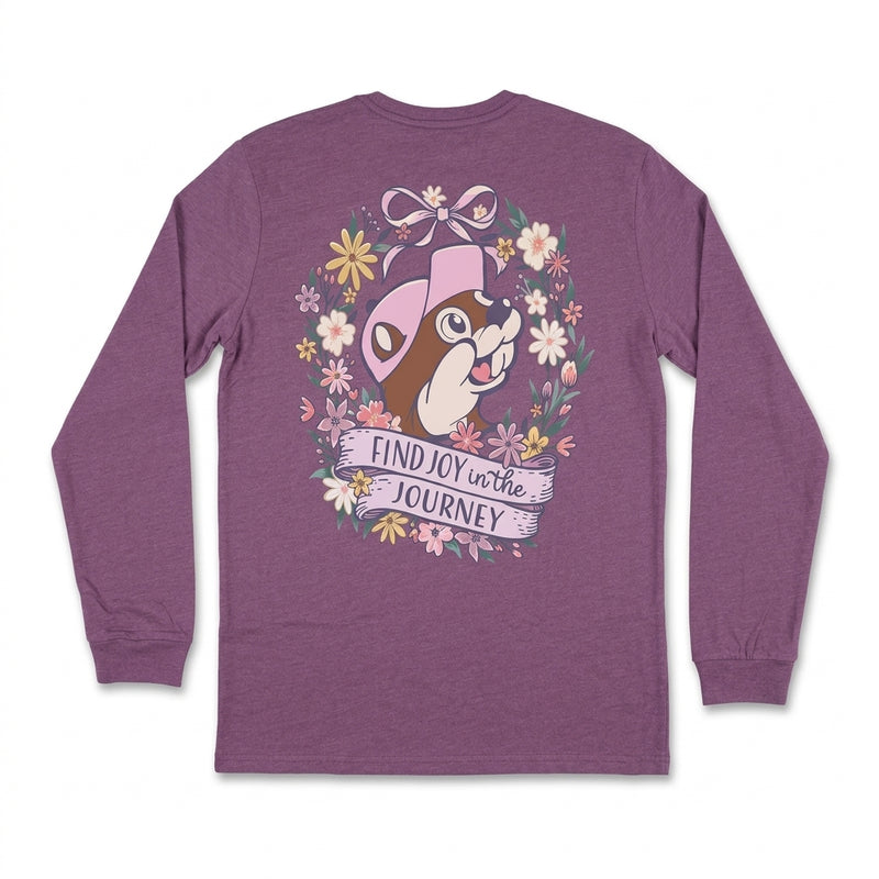 Back view of a heathered purple long-sleeve t-shirt featuring Buc-ee in a pink hat surrounded by a floral wreath, ribbon bow, and a banner reading "Find Joy in the Journey".