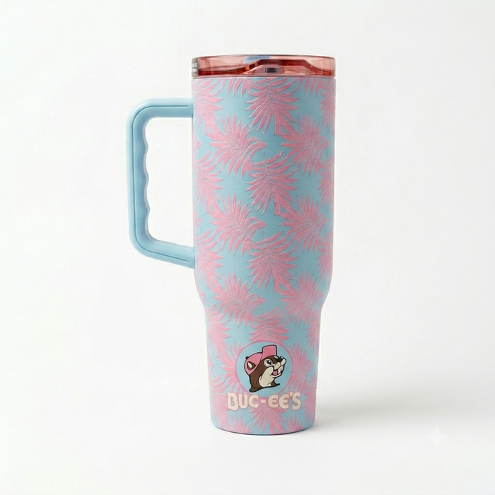 The back view of a 40-ounce Buc-ee's Fit Forty Pro travel tumbler showing the continuous pink palm leaf pattern over a light blue background. A large, light blue ergonomic handle with molded finger grooves is attached to the left side, and a small, circular Buc-ee's beaver logo is positioned near the tapered base. Displayed on a white background.