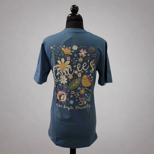 Back view of a blue Buc-ee’s t-shirt with a large floral Buc-ee’s graphic, Buc-ee’s script, and the phrase “Live Simple, Dream Big,” displayed on a mannequin.