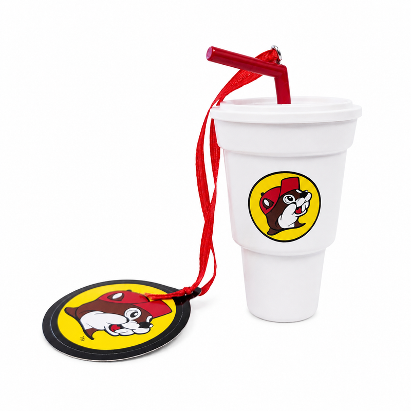 Miniature white Buc-ee’s fountain drink cup Christmas ornament featuring a red straw, beaver logo, and red hanging ribbon next to a round Buc-ee's tag.