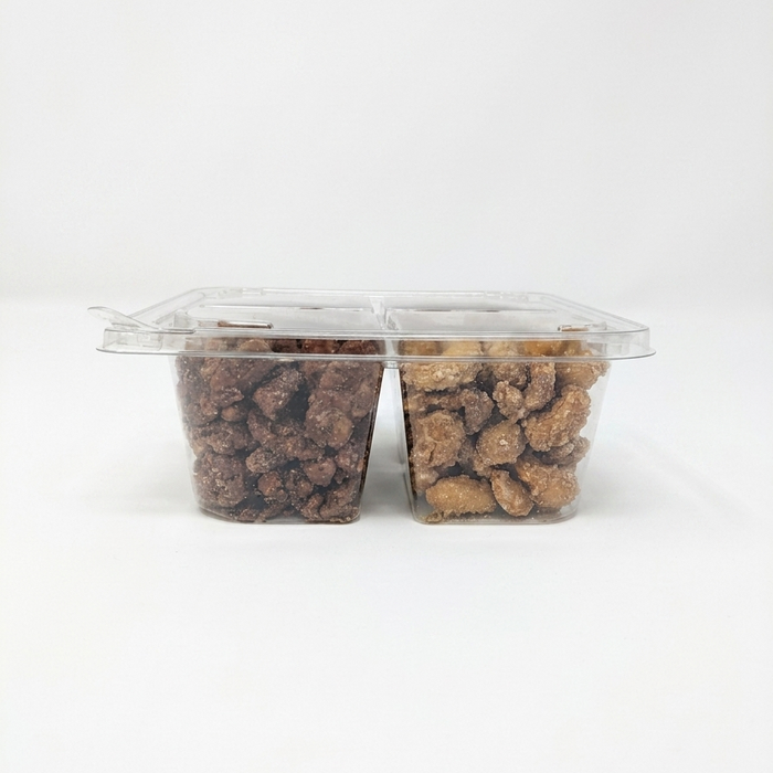 A side-profile product shot of a 4-compartment clear plastic tray filled with glazed nuts, shown against a seamless white background. This view highlights the depth of the containers, showing the generous portions of dark glazed pecans and golden glazed cashews through the transparent plastic walls. The flat, clear lid is securely fastened on top.