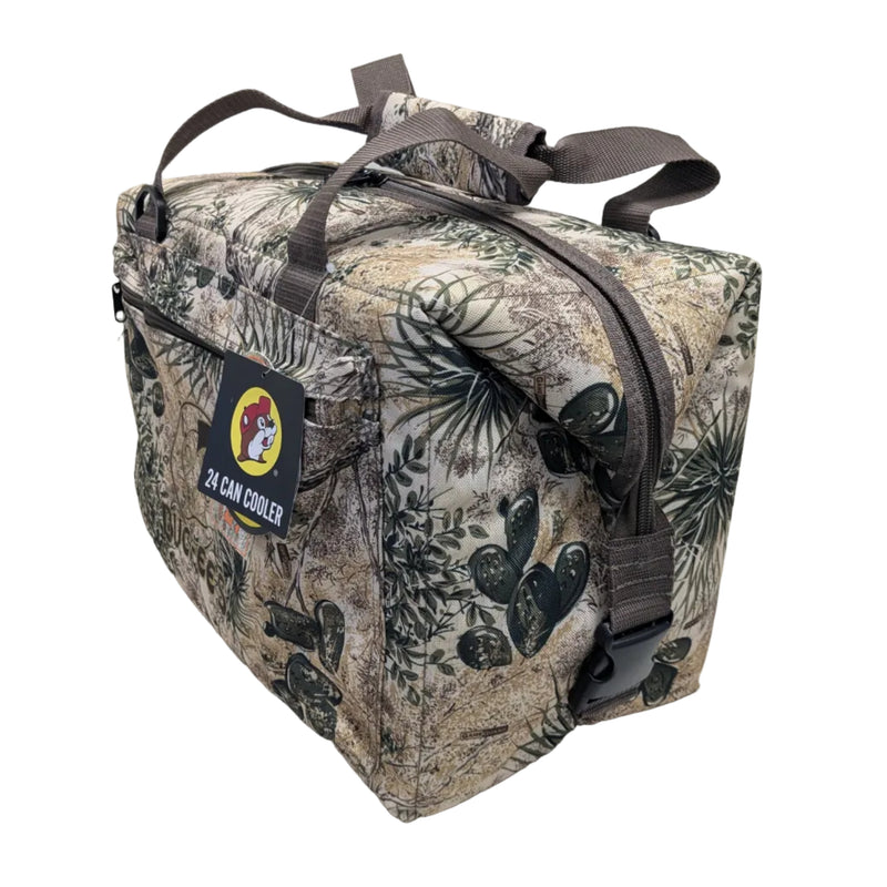 A side view of a Buc-ee's GameGuard 24 Can  Cooler, showing the buckles that can be cliped together to show the rectangular shape of the soft-sided cooler bag featuring a realistic Texas brush country camouflage print with prickly pear cactus details.  The top has brown webbed carrying handles with a padded grip wrap. Displayed on a white background.