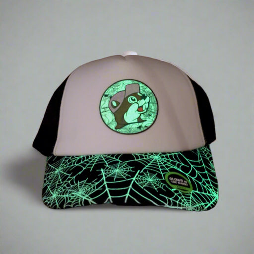 Buc-ee’s glow-in-the-dark trucker hat glowing in a dark room, highlighting the spiderweb brim and logo