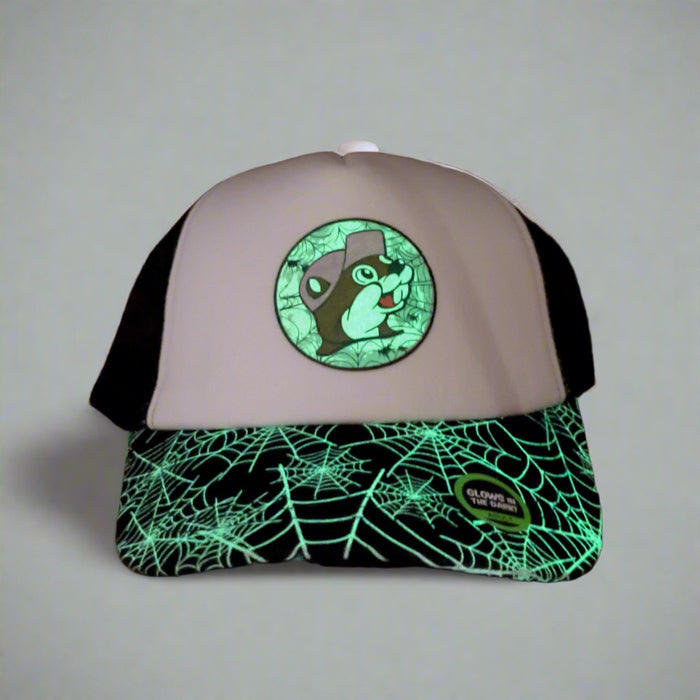 Buc-ee’s glow-in-the-dark trucker hat glowing in a dark room, highlighting the spiderweb brim and logo
